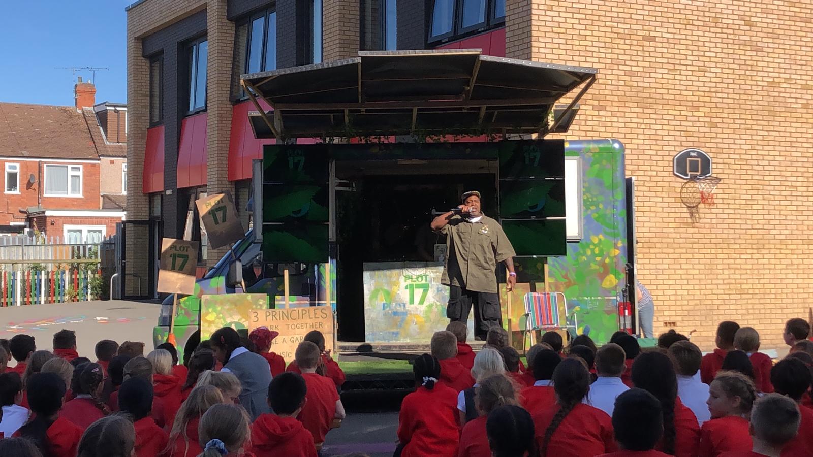 Photo of primary school children listening to a performance of Plot 17 by Kenny Baraka
