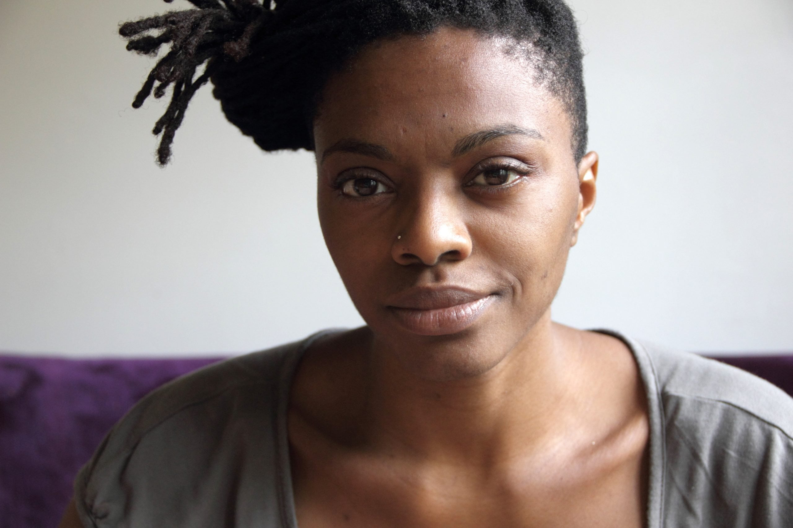 Photo of a woman with brown eyes and a nose piercing looking directly to the camera
